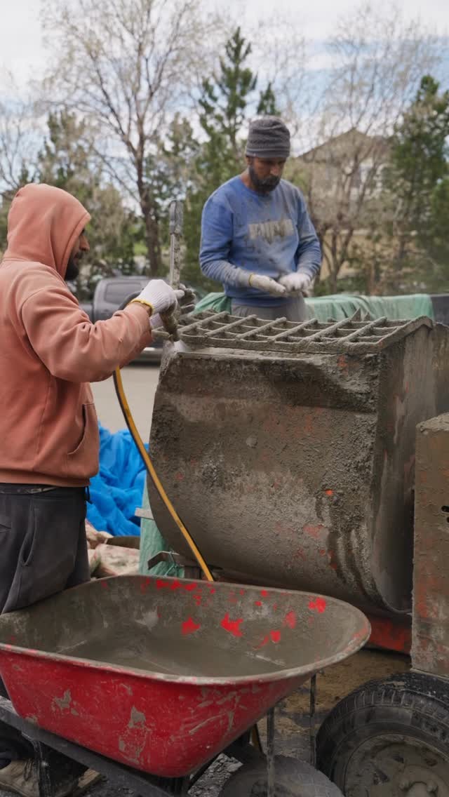 Divine Stucco crew mixing stucco base coat on site beside a mixer and wheelbarrow