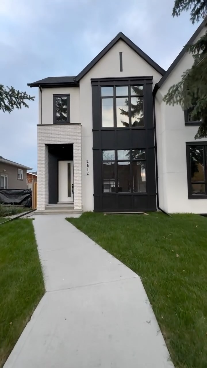 White smooth stucco home with black window trim and a white brick entry