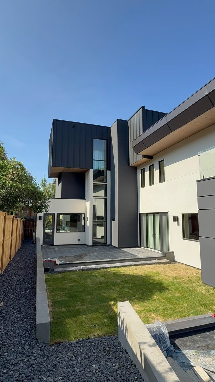 Modern custom home rear exterior with two-tone stucco and a paved patio