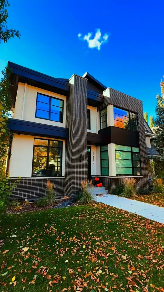 Two-tone Calgary home with light stucco, dark brick columns and autumn landscaping