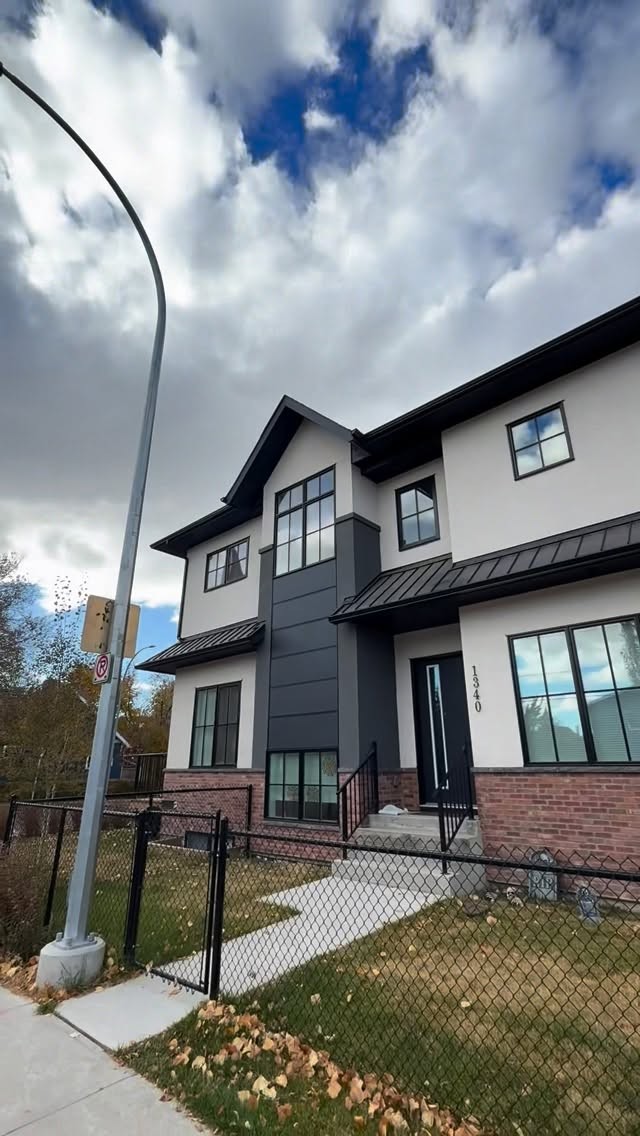 Corner-lot home with white acrylic stucco, charcoal accents and brick foundation